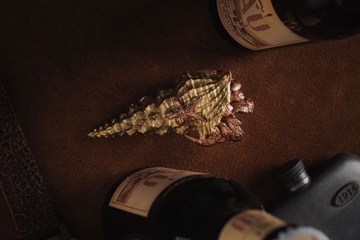 Top view of a golden seashell with a decorative starfish, surrounded by vintage bottles.