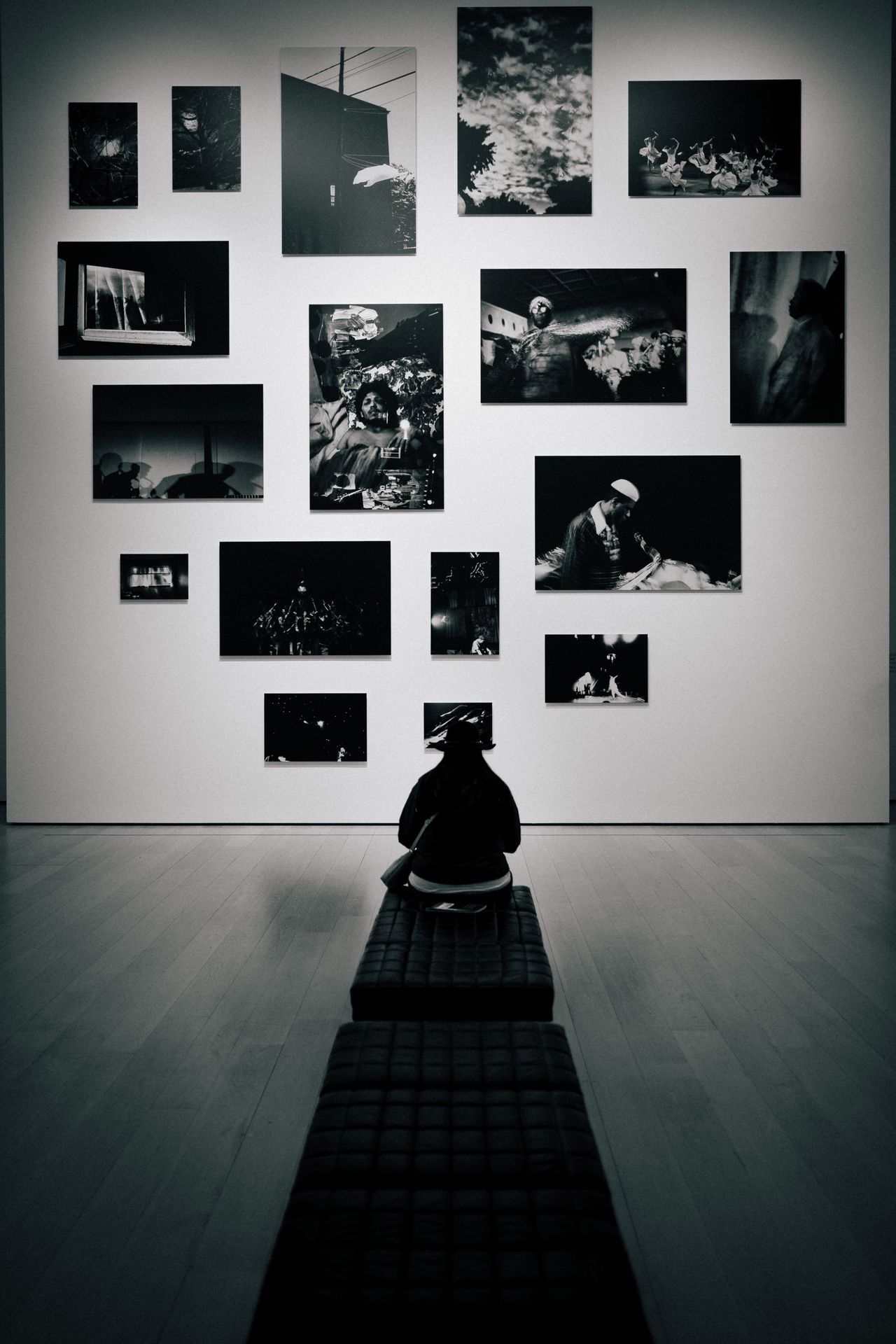 A person sitting on a gallery bench, focused intensely on just photographs.