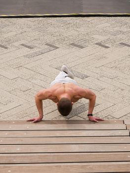 Fit man performing a push-up exercise outdoors, showcasing strong back muscles and fitness routine.