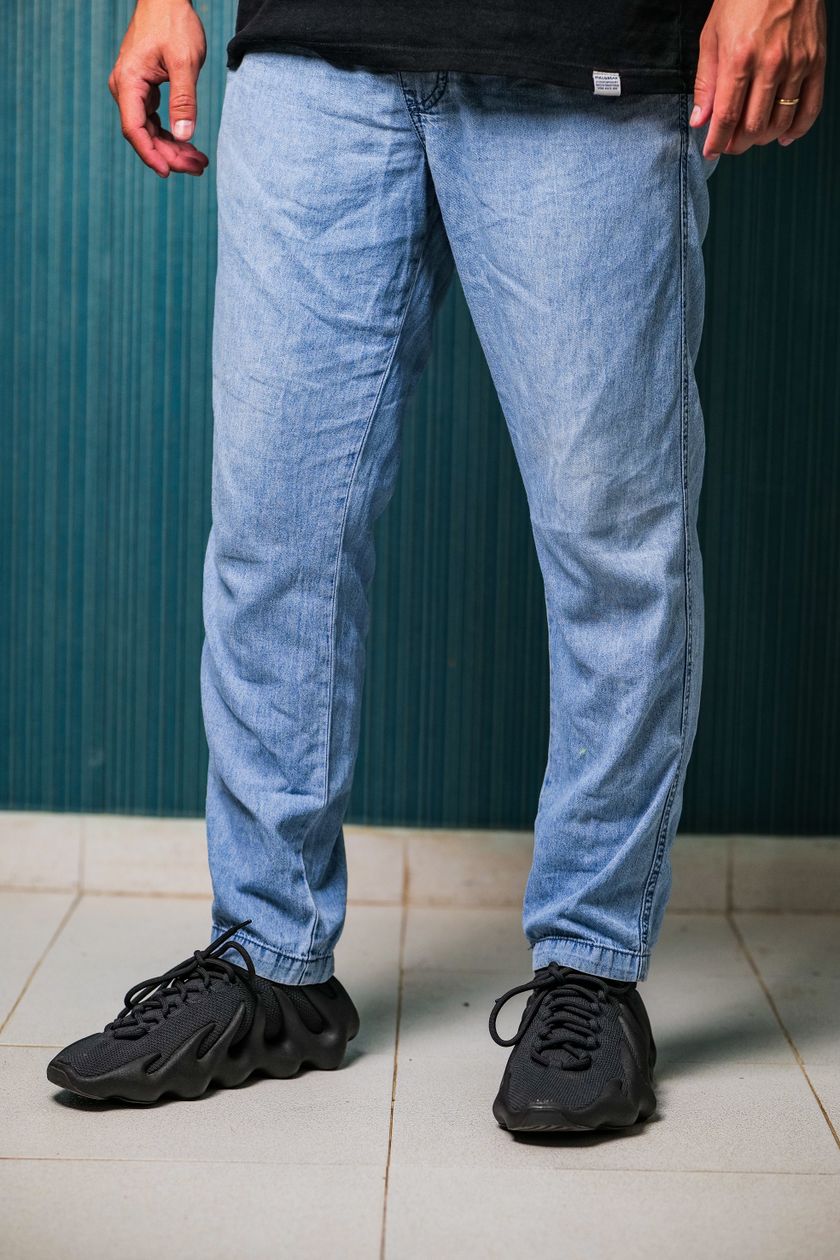 Blue denim jeans worn on the body, waist to hem, with black sneakers