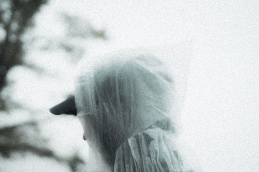 A moody close-up portrait of a man wearing a rain poncho, evoking a sense of solitude and introspection. Stock Photo