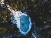 白雪覆盖的森林环绕着冰冻的湖泊，构成了一幅令人叹为观止的鸟瞰图