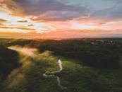 日落时分，空中拍摄的森林景观令人惊叹，蜿蜒的河流与充满活力的天空色彩交相辉映