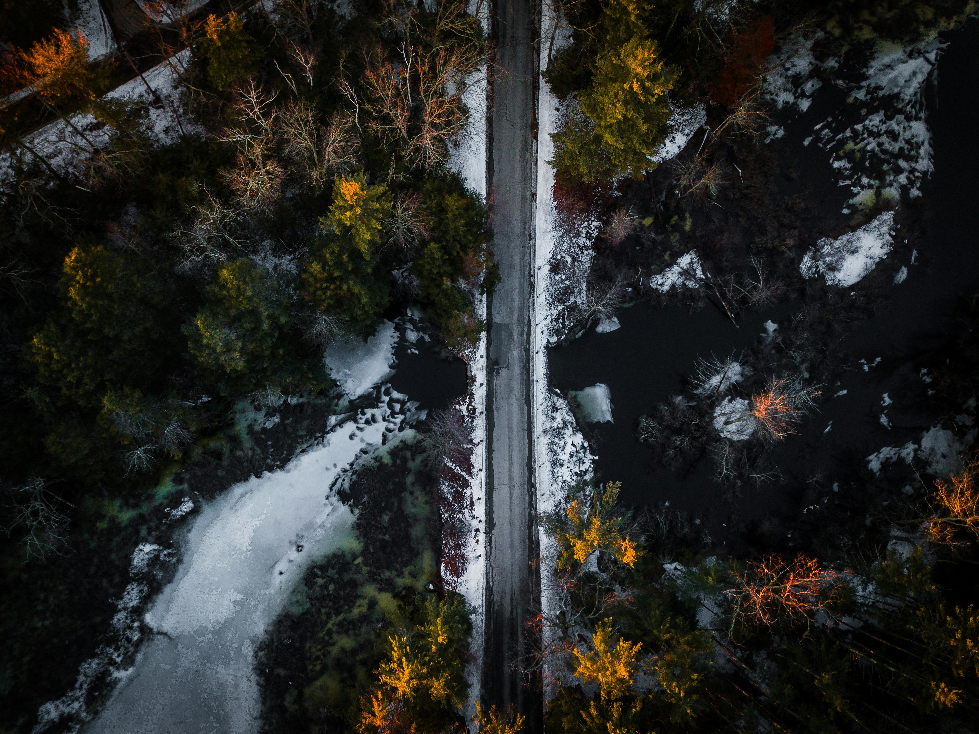 无人机拍摄了一条冬天穿过白雪皑皑森林的道路