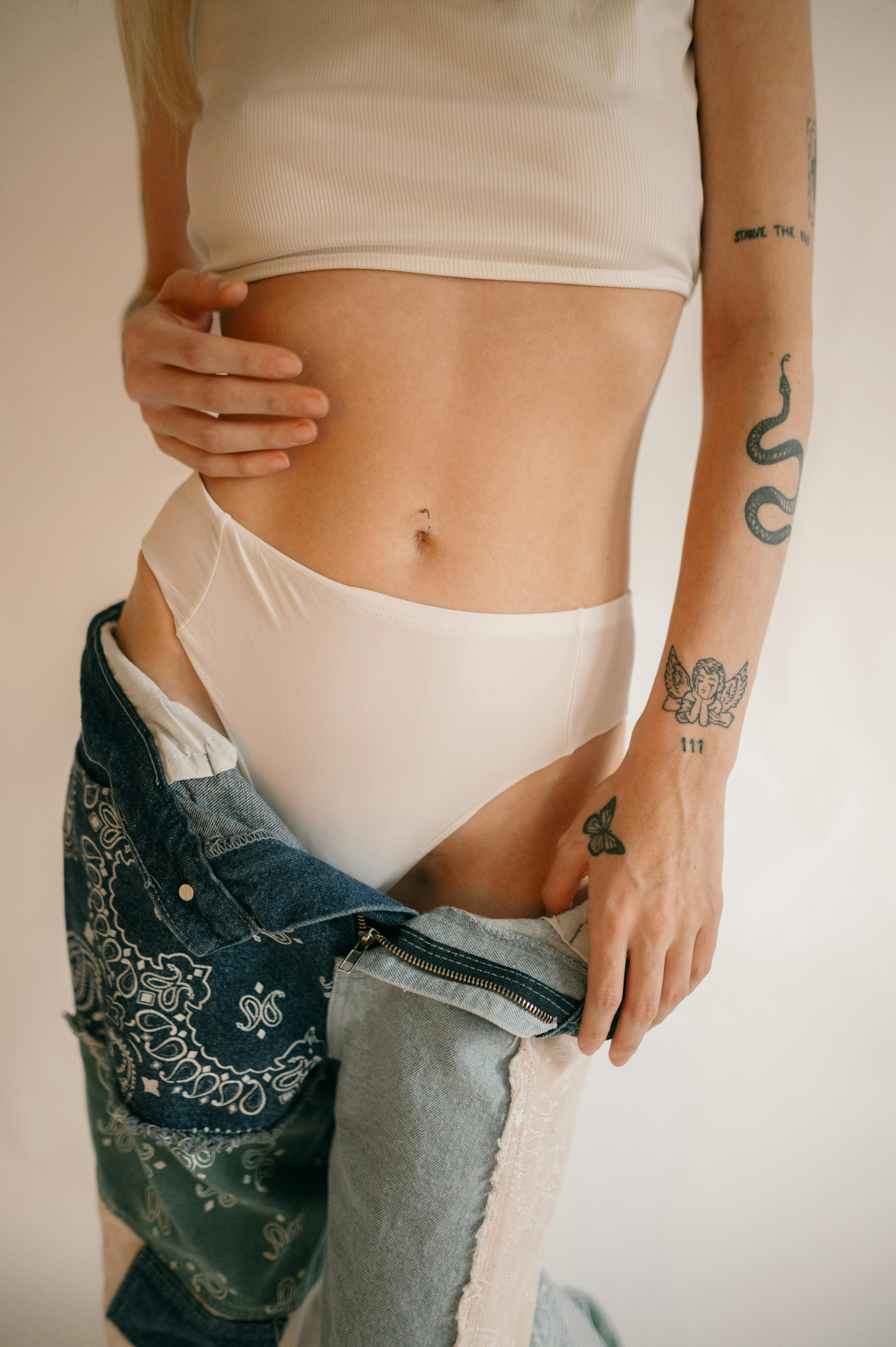 Elegant fashion portrait featuring tattoos, denim, and minimalist style.