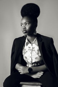 A black and white portrait showcasing a stylish woman seated elegantly, exuding confidence.