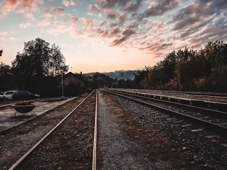 夕阳西下，五彩斑斓的天空映衬着被大自然环抱的宁静铁路轨道