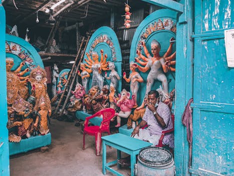 A workshop in Kolkata showcasing colorful Hindu deity sculptures and a craftsman working.
