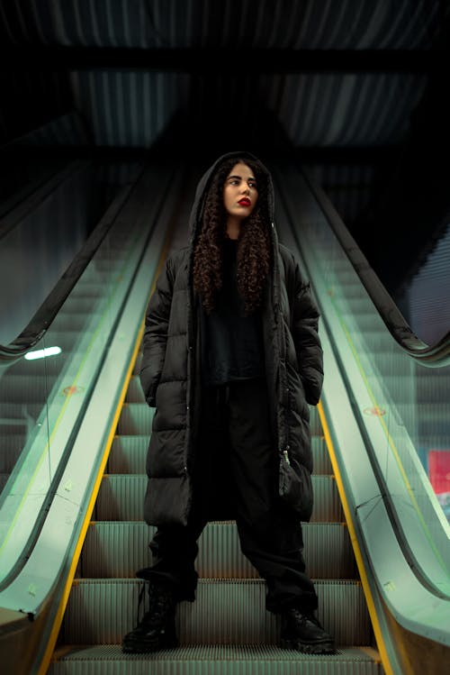 Woman in Jacket Standing on Escalator