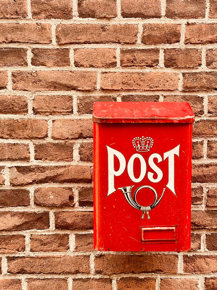 A Vintage Red Mailbox Attached To A Brick Wall 