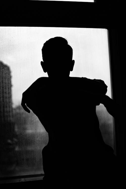 Silhouette of a Man Standing by the Window 