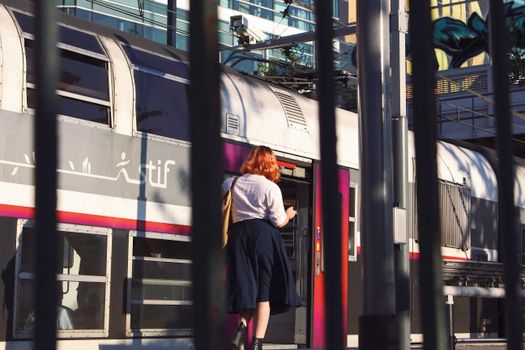 Woman enters a train at Paris station, capturing urban transit moment.