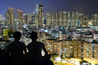 两人在夜晚俯瞰明亮的城市天际线，捕捉城市美景