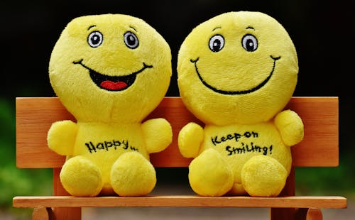 Two Yellow Plushtoy on Brown Bench