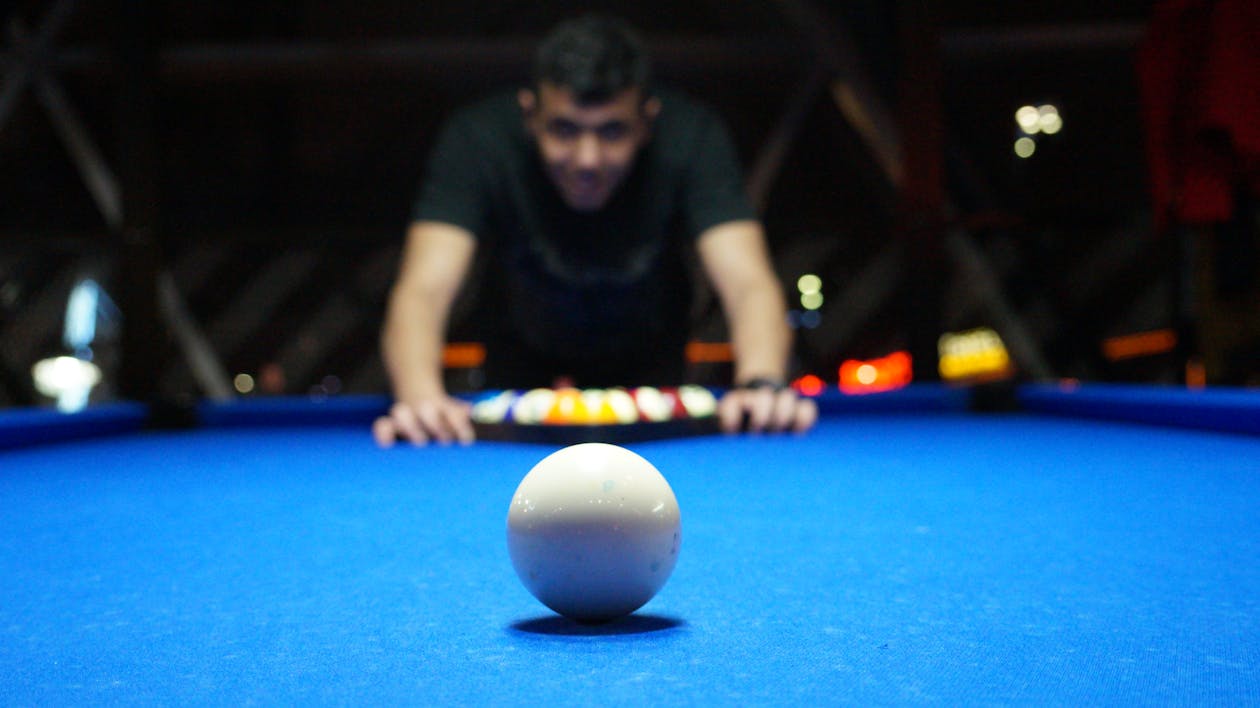 Free Man Playing Pool Table While Sharply Looking at the White Ball on the Table Stock Photo