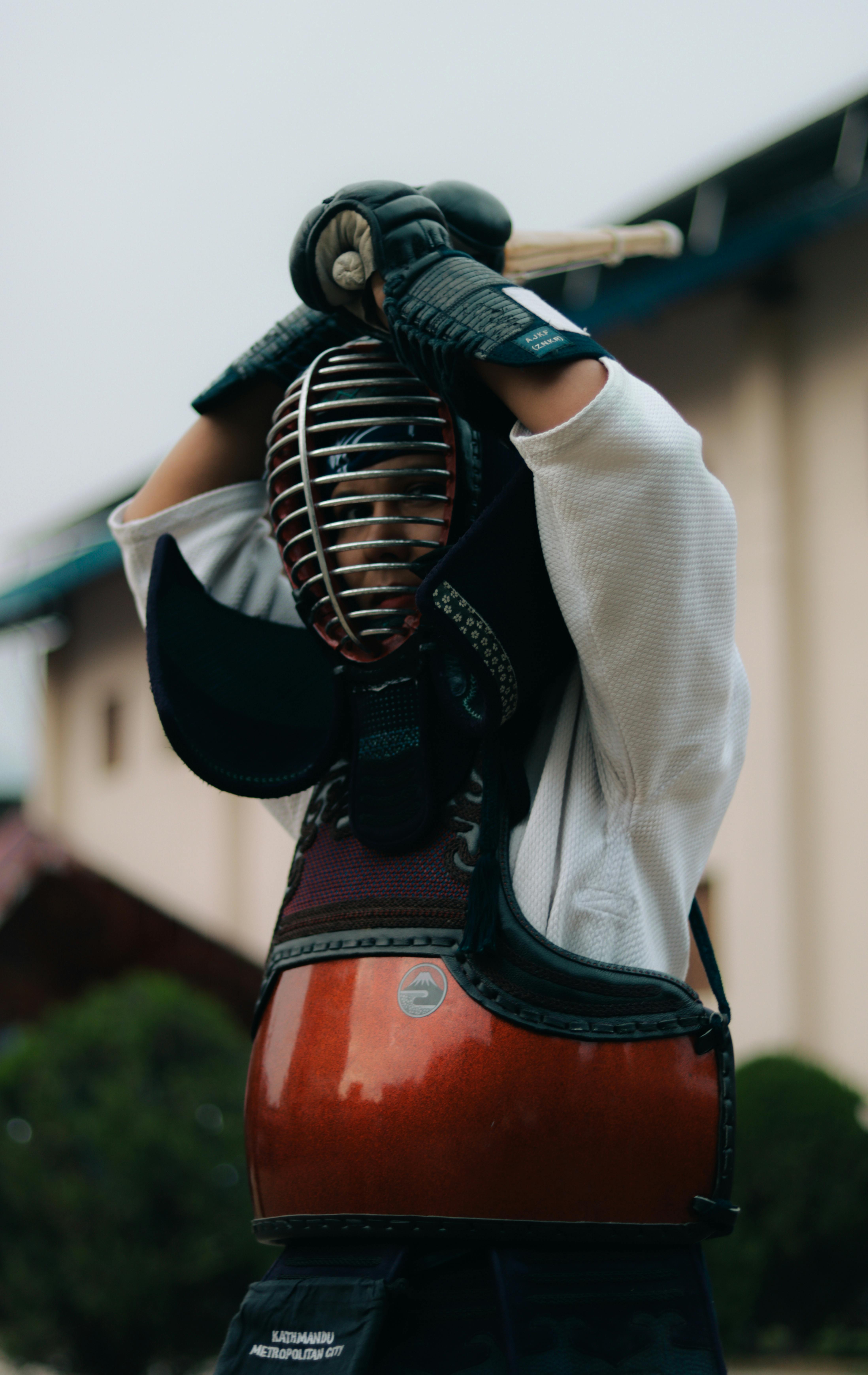 A kendo practitioner in full armor with sword outdoors, capturing traditional martial arts.