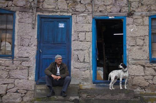 Man Sitting with Dog near House