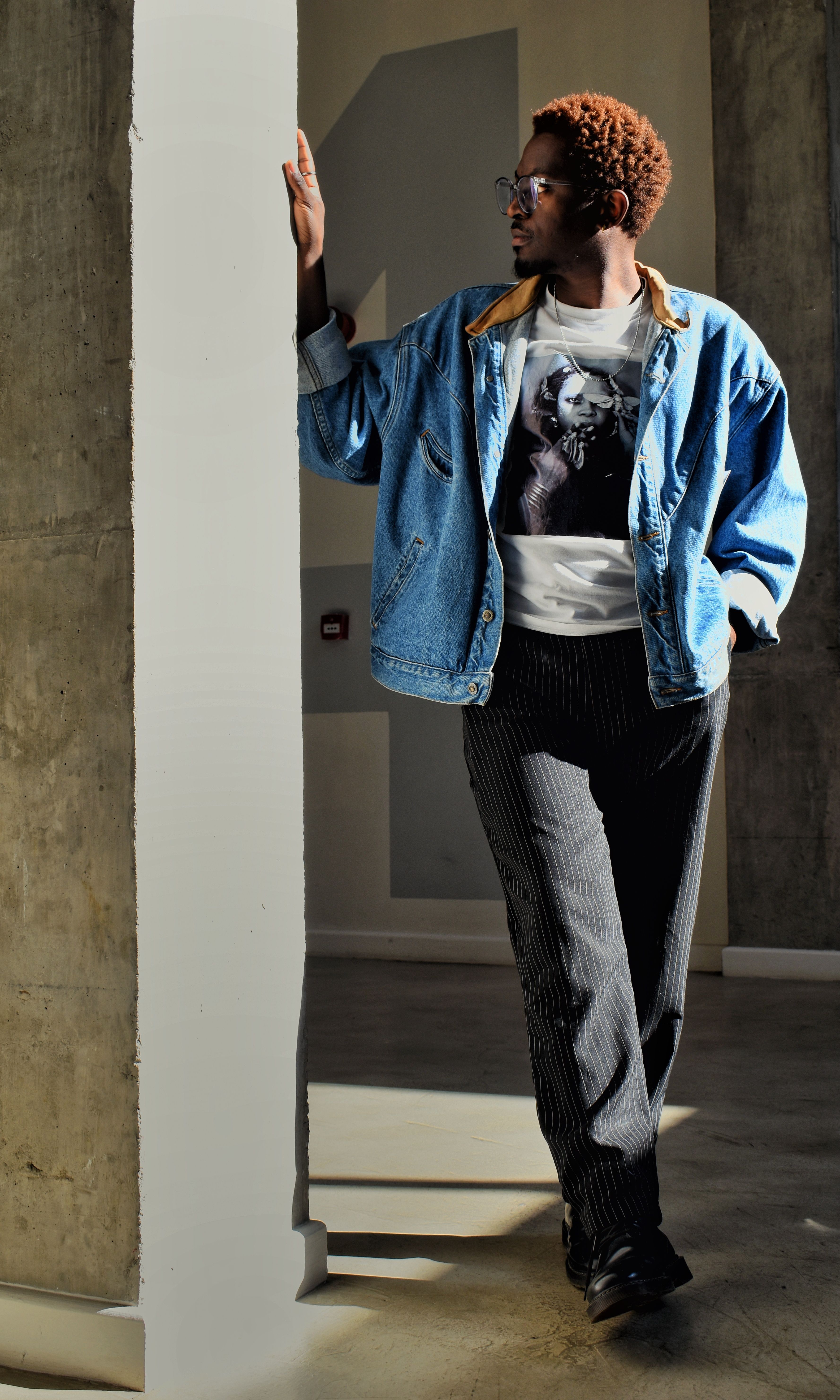 Stylish man in denim jacket leans against a pillar in Lusaka interior.
