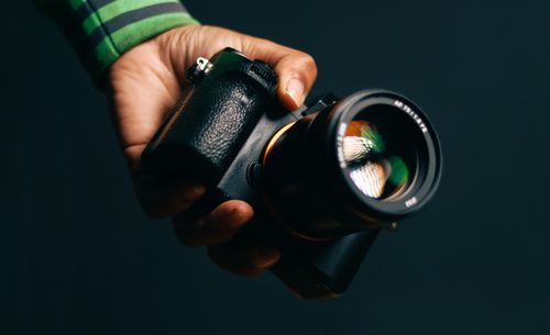 Free A person holding a camera against a black background, perfect for photography concepts. Stock Photo