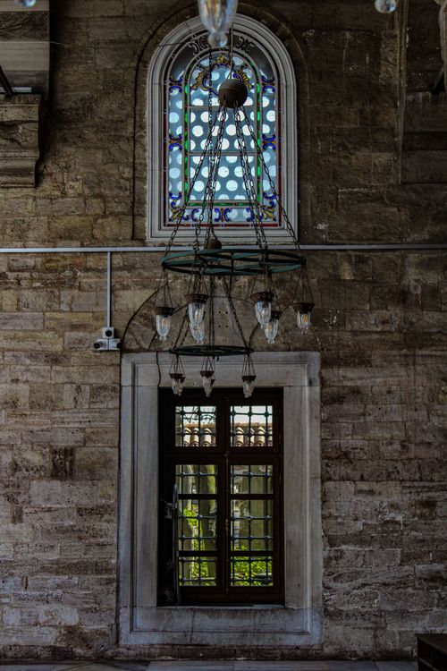 Free A historical stone interior with a hanging chandelier and stained glass window. Stock Photo
