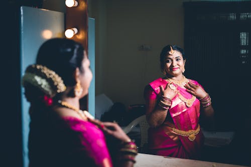 Smiling Woman in Traditional Clothing Standing by Mirror