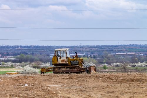 Free Old bulldozer on a barren field with a cloudy sky, showcasing industrial decay in a rural setting. Stock Photo