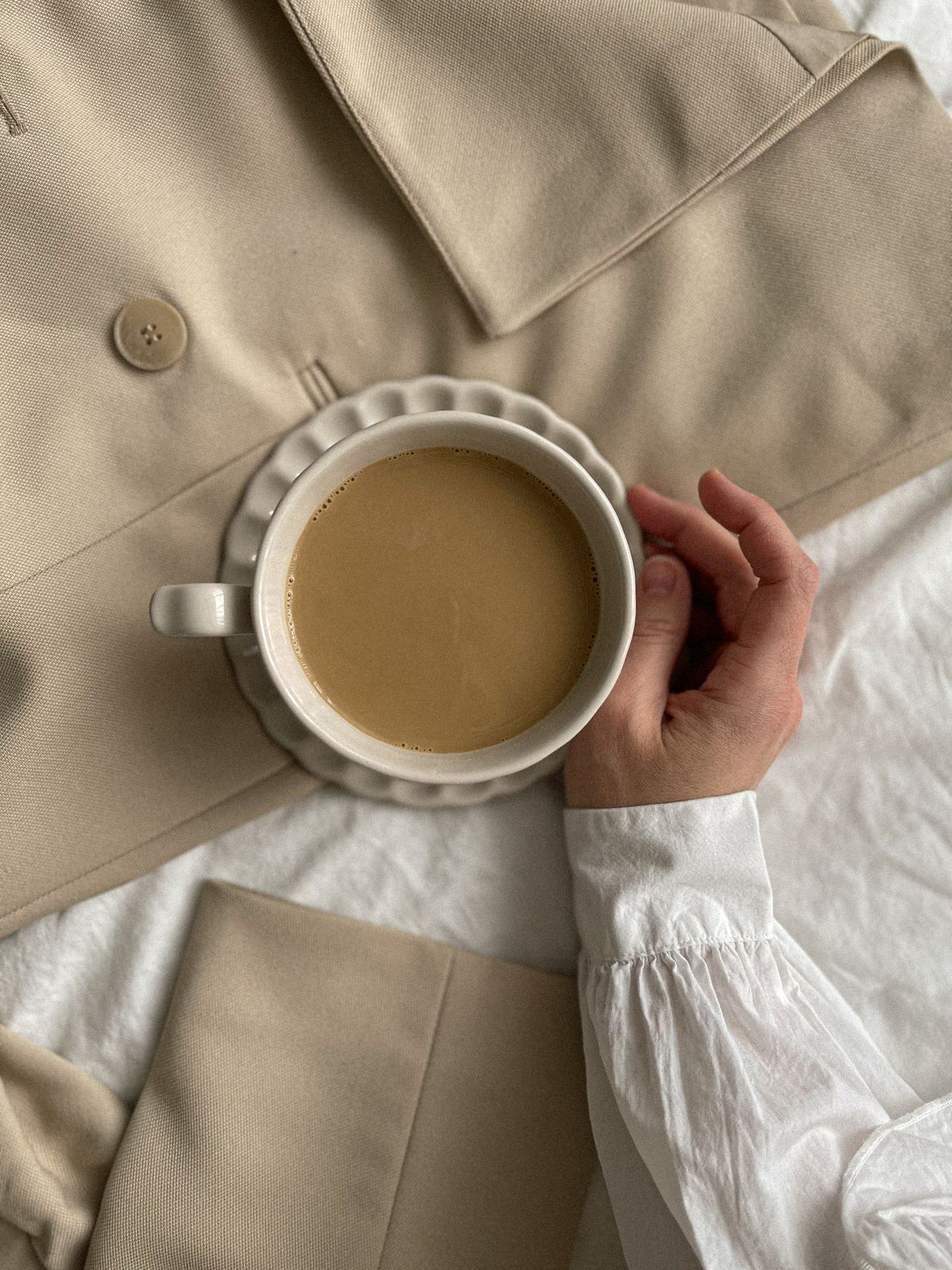 A hand holding coffee in a warm neutral lifestyle setting