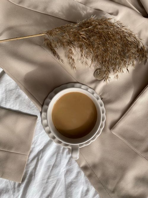 Free Minimalist composition of coffee cup on beige fabric and dried flower, offering a warm and cozy feel. Stock Photo