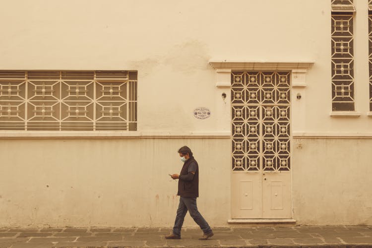 Man In Mask Walking Near Building