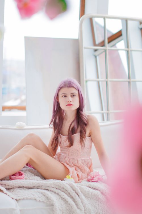 Free Portrait of a fashionable woman with pink hair sitting comfortably indoors in a modern setting. Stock Photo
