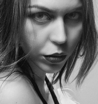 Close-up black and white portrait of a woman with long hair and an intense gaze in a vertical shot.