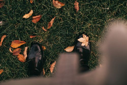 Free Black boots on green grass with scattered autumn leaves, offering a cozy fall vibe. Stock Photo