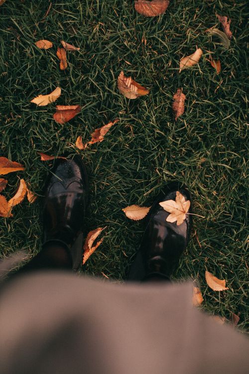 Outdoor boots on grass among fallen autumn leaves