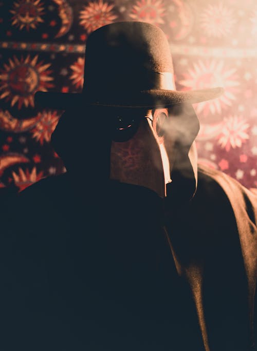 бесплатная Человек в черном пальто и шляпе с маской чумного доктора Стоковое фото