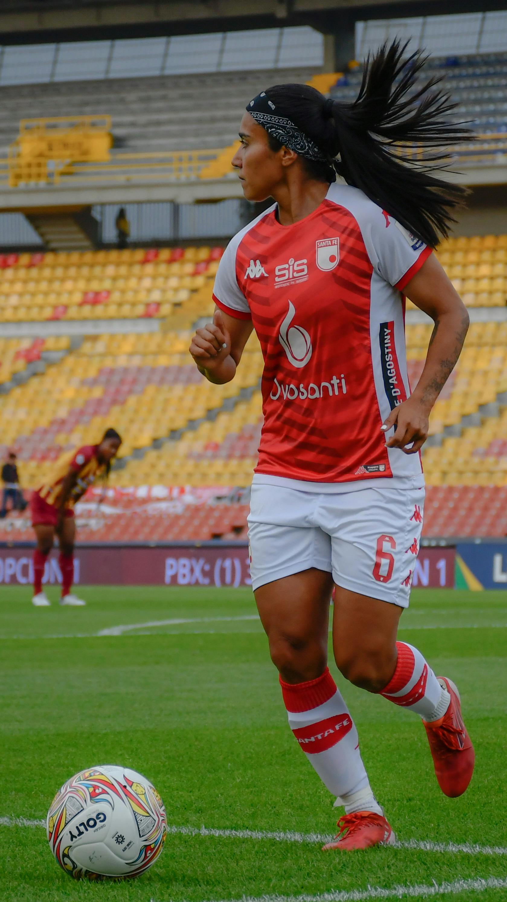 Action shot of a female soccer player in a stadium preparing for a move during a match.