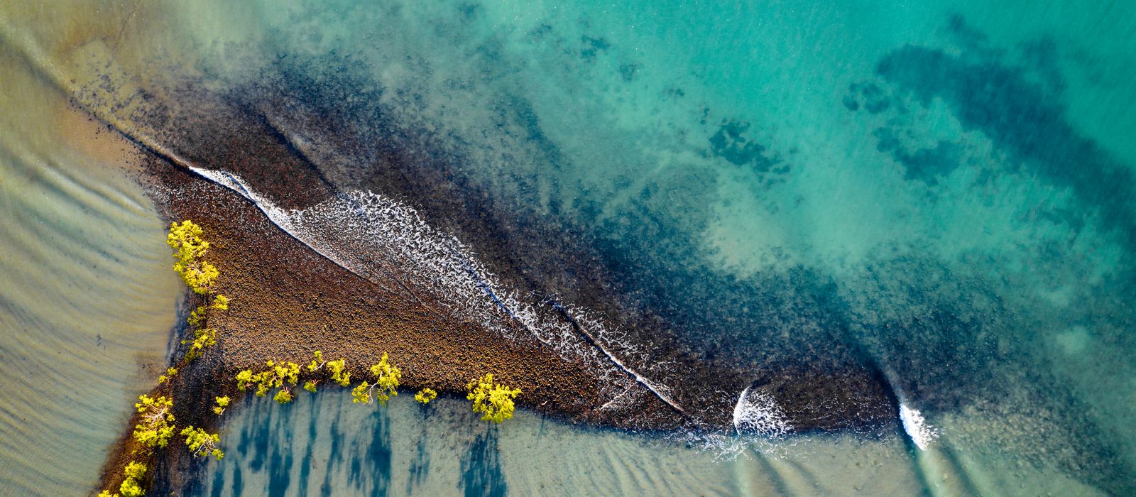 Stunning aerial shot of Port Douglas beach with clear turquoise waters and sandy shoreline.