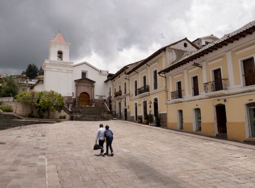 Free A historic church and cobblestone square in Quito, Ecuador, with people walking through the charming colonial architecture. Stock Photo