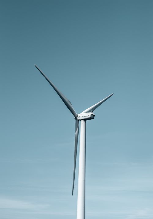 Free A wind turbine captured from a low angle against a clear blue sky, emphasizing renewable energy. Stock Photo