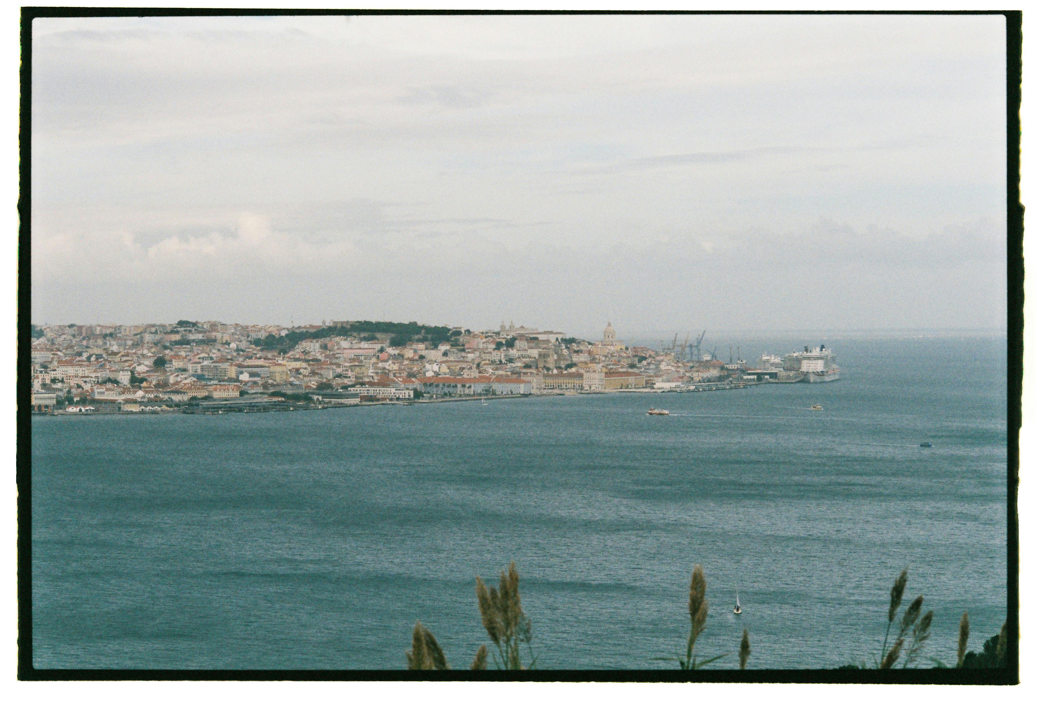 A picturesque view of Lisbon's coastline, capturing historic architecture and the vast sea.