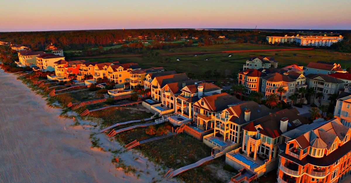 Stunning aerial shot of luxurious beachfront homes on Hilton Head Island at sunset, showcasing coastal beauty.