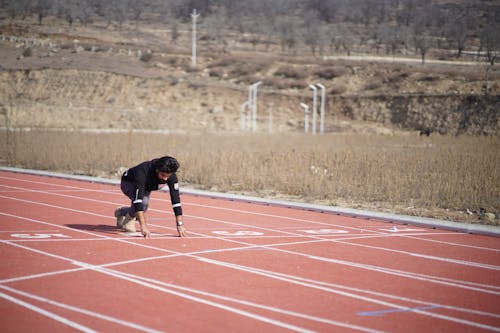Man Kneeling at Starting Line on Race Track