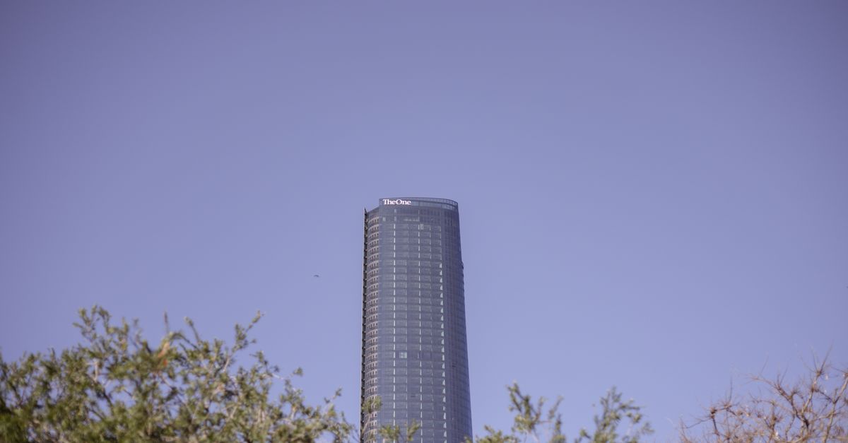 A sleek view of The One Tower in Brisbane against a clear sky, surrounded by trees.