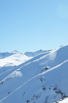 Serene view of snow-covered mountains against a clear blue sky. Perfect for winter travel themes.