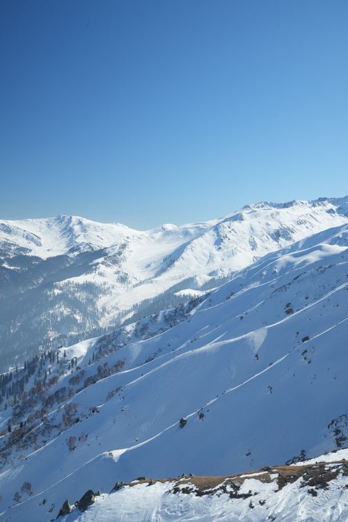Free A breathtaking view of a snow-covered mountain range under a clear blue sky, showcasing winter beauty. Stock Photo