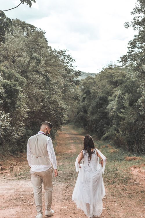 Free Newlyweds strolling on a scenic country road, exuding romance and serenity. Stock Photo