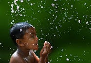 一个快乐的孩子在绿色背景下开心地玩着水滴