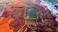 令人惊叹的沿海游泳池鸟瞰图，日落时色彩缤纷的岩石环境和海浪