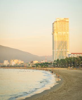 Scenic view of Quy Nhơn's skyline and beach during sunset, featuring a prominent skyscraper.
