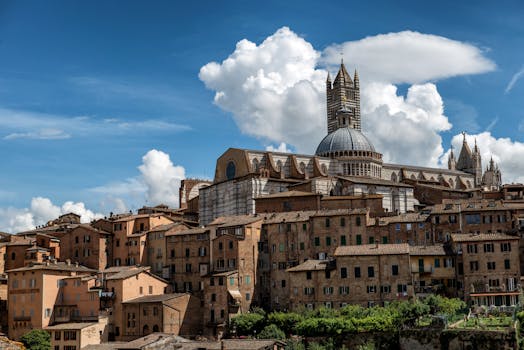 The Siena Cathedral standing elegantly over the historic cityscape under a vibrant blue sky.