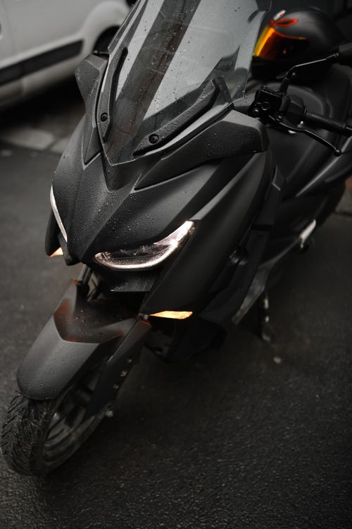 Free Close-up of a sleek modern scooter with rain droplets on a wet road. Stock Photo